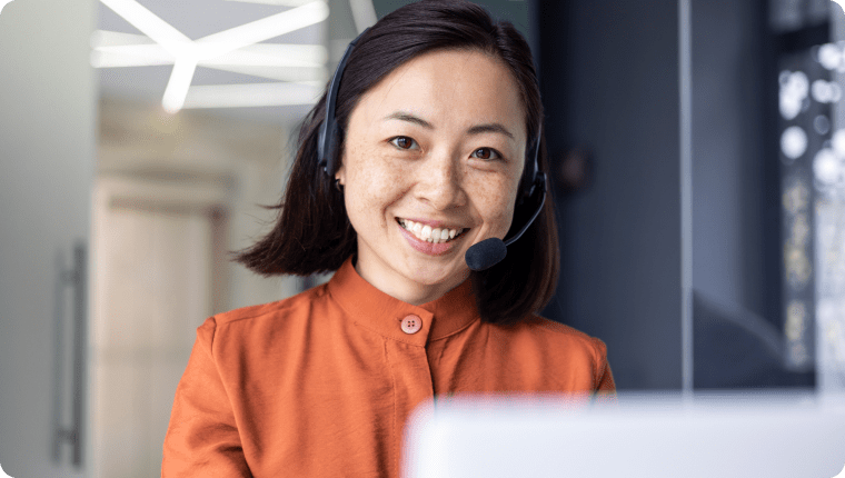 Asian woman wearing headphones, providing customer support remotely